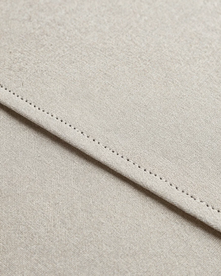 Textile seam and fabric edge in close detail, neutral tones, soft even daylight, crisp stitch detail, editorial textile